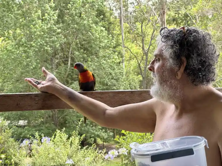 Joff feeding birds on his deck at his home ni Byrrill Creek in 2023